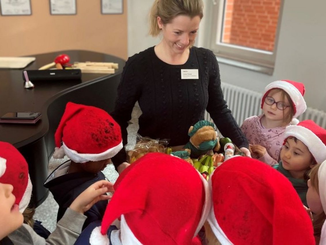 Eine Frau überreicht Kindern eine Kiste mit Obst, Gemüse und Süßigkeiten