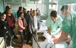 Schüler zeigen im ATLAS-Trainingszentrum an einer Puppe die tägliche Arbeit im Klinikum